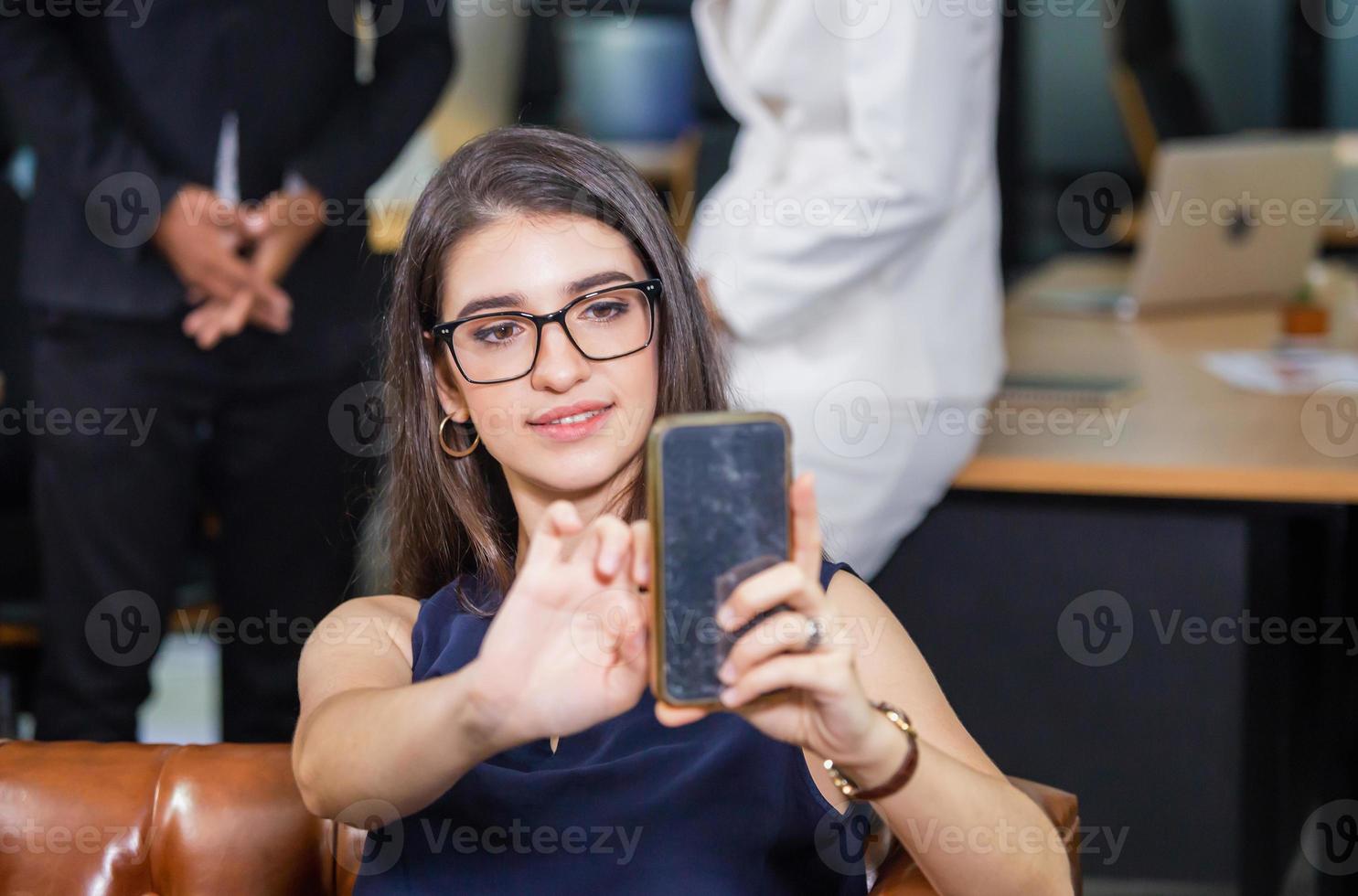 alegre mujer casual tomando selfie relajándose en la oficina moderna foto