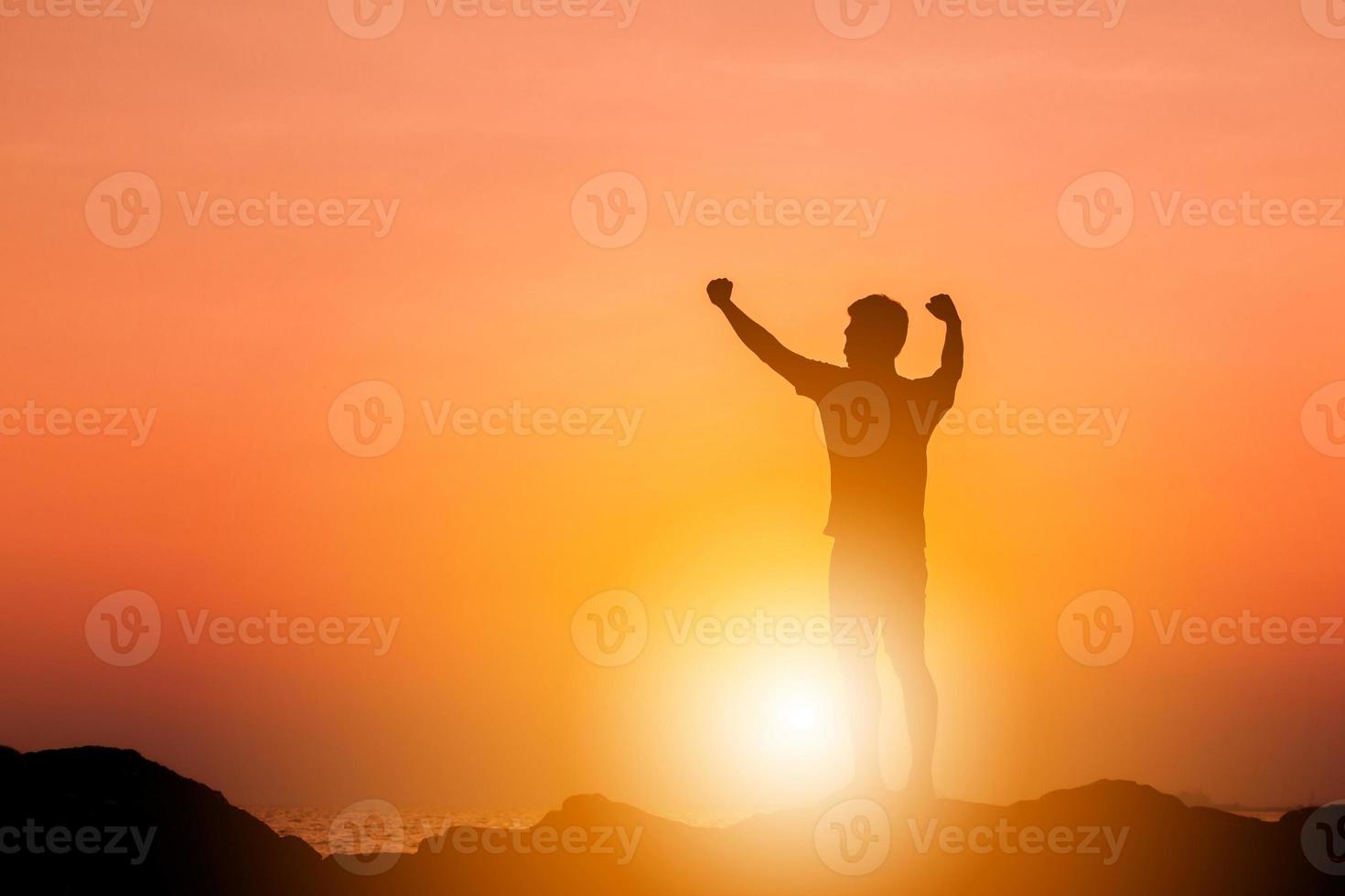 Silhouette of Man Celebration Success Happiness on a Stone Evening Sky Sunset at Beach Background, Sport and active life Concept. photo