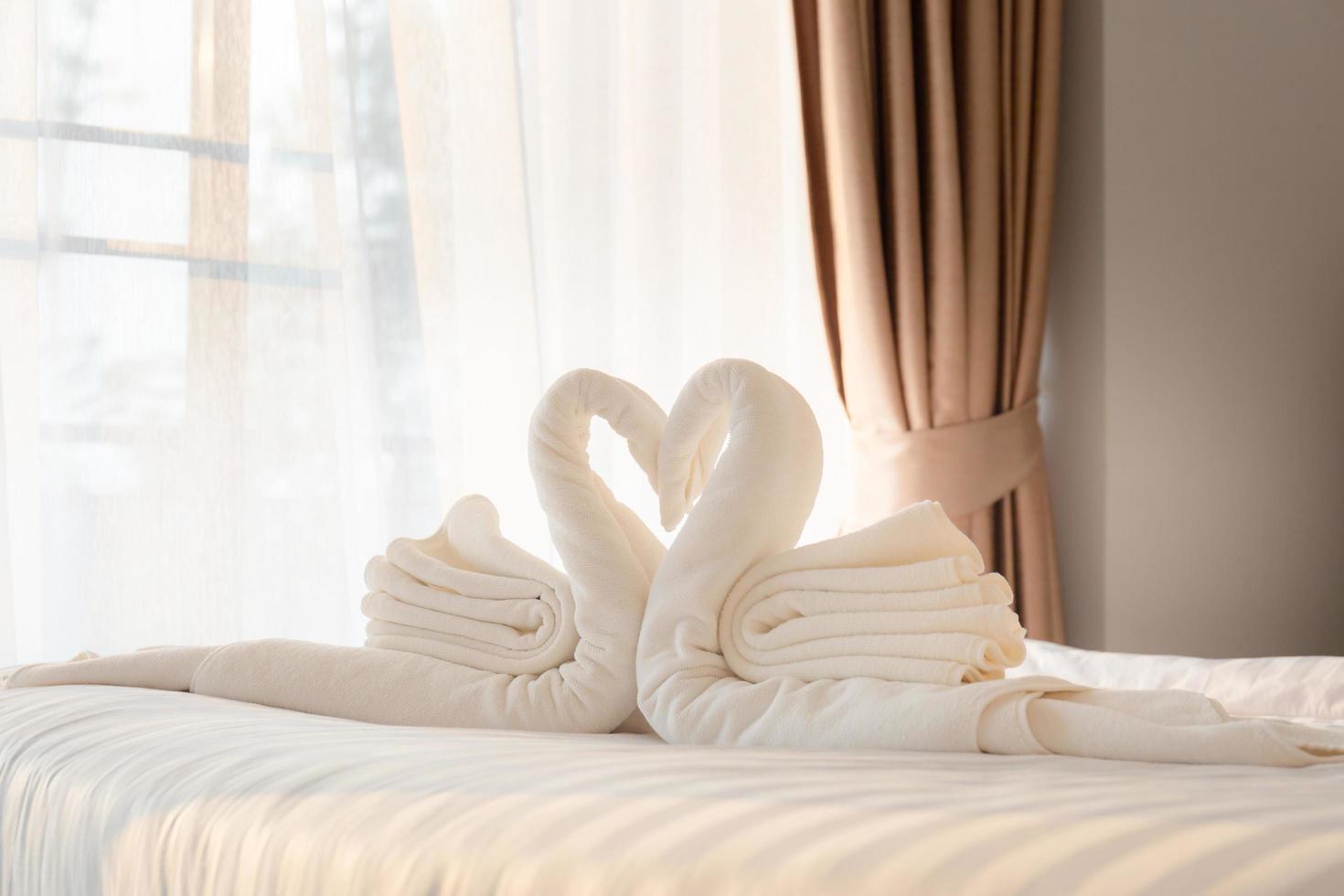 Towel folded in swan shape on bed sheet in bed room photo