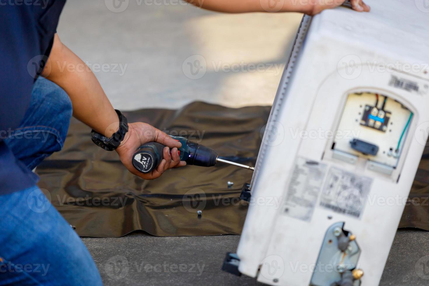 Air Conditioning Repair, technician man hands using a screwdriver fixing modern air conditioning system photo