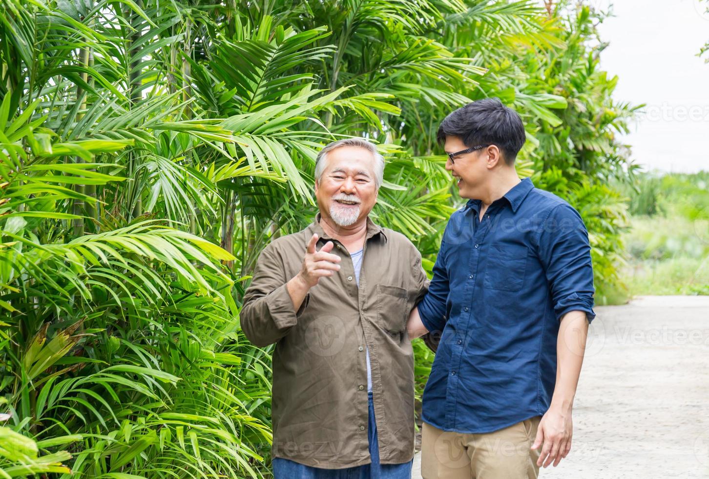 el padre asiático mayor y el hijo de mediana edad caminan en el parque, conceptos familiares de felicidad en asia foto