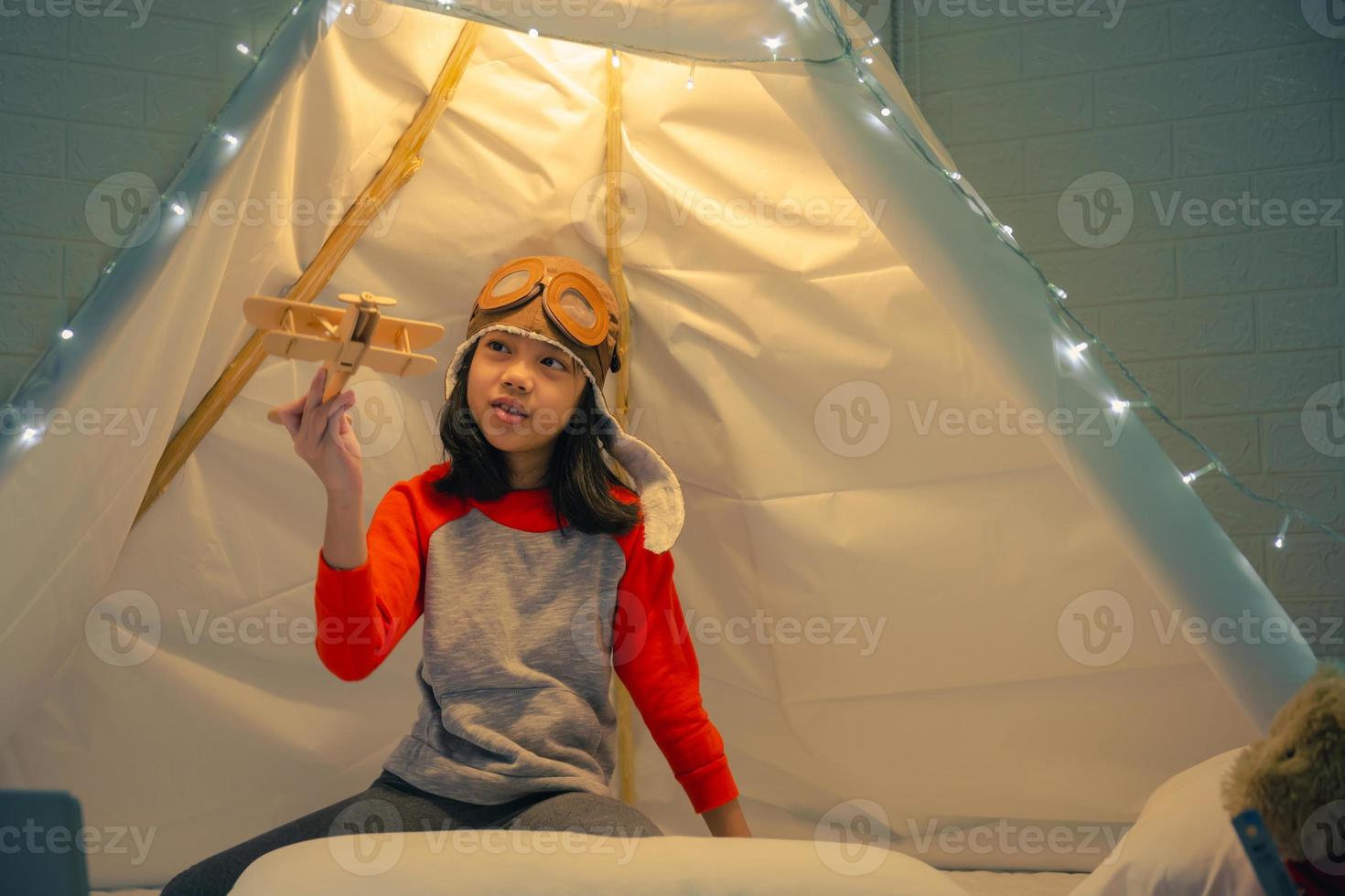 niña feliz jugando en la tienda de campaña en casa, niño divertido y encantador divirtiéndose en la habitación de los niños. foto