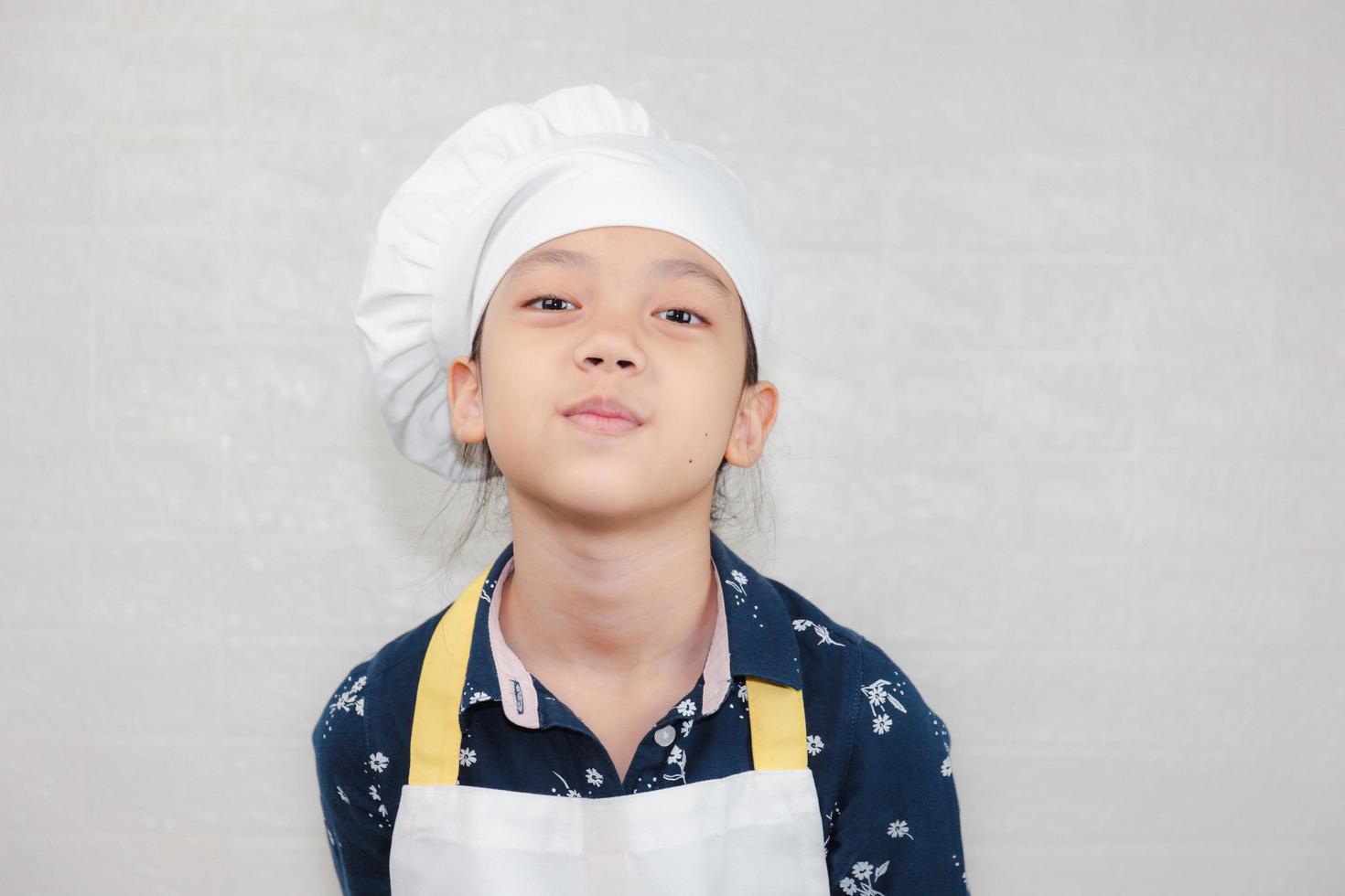 concepto de carreras de ensueño, retrato de niño feliz chef mirando la cámara con fondo borroso foto