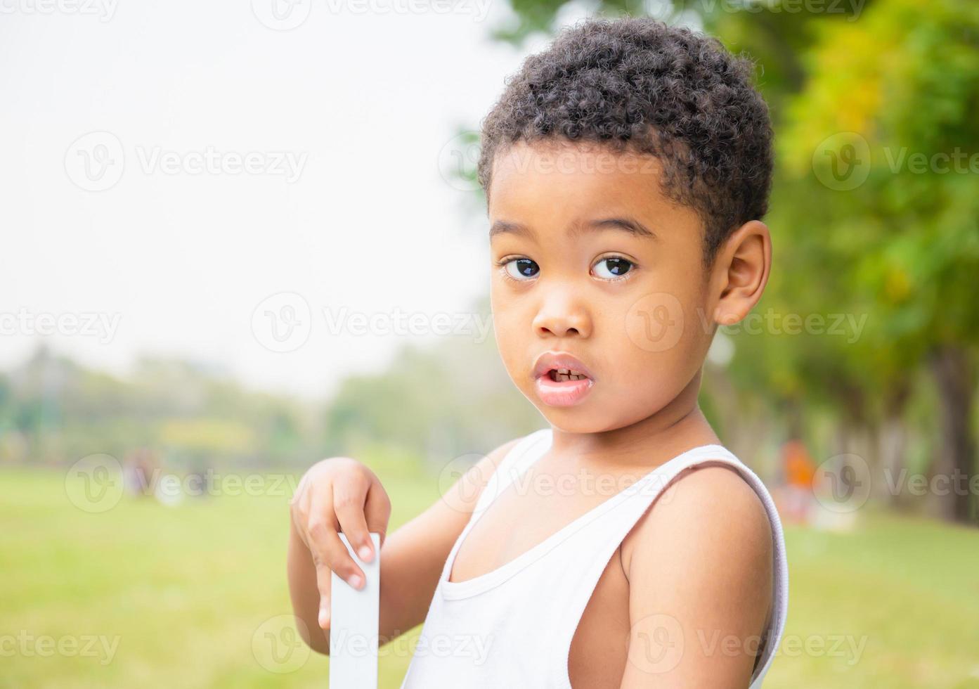 Portrait of little boy playing outdoors in a park and looking at camera, Kids concept. photo