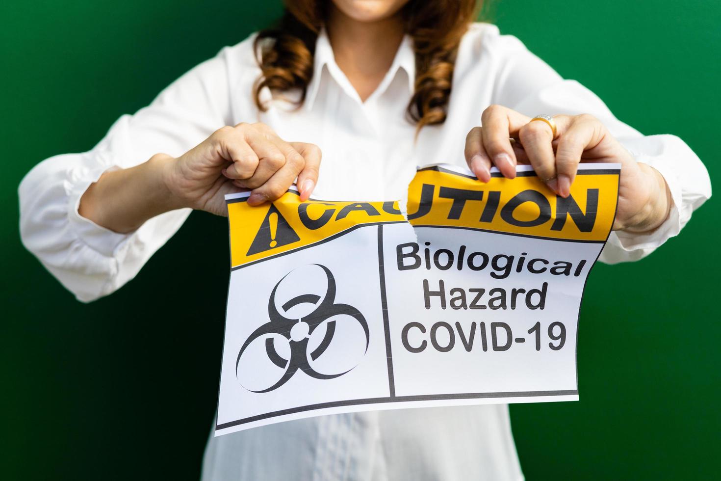 Woman holding and tearing paper with Covid-19 caution of biological hazard words. The idea or concept for happiness, free, and wellness after finishing and recovered from Coronarivus. photo