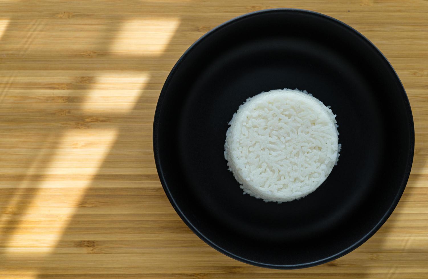 Thai style cooking steam rice put on black plate on wooden background with copy space. Top view angle. photo