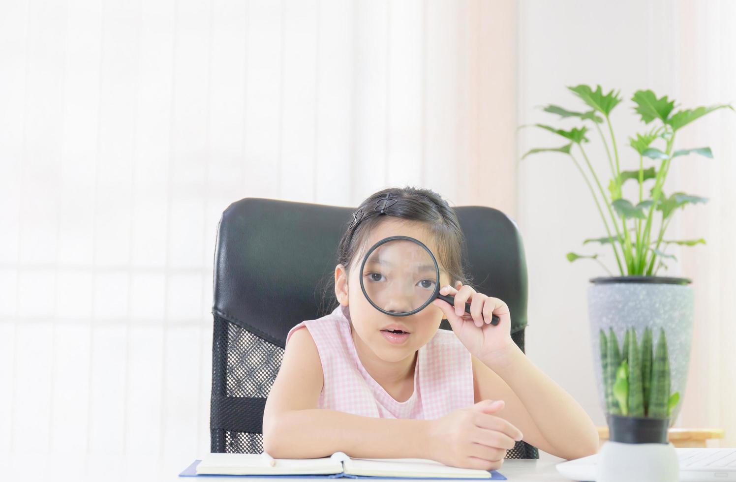 Cheerful little smiling girl with a magnifying glass, Education and learn from home concept photo