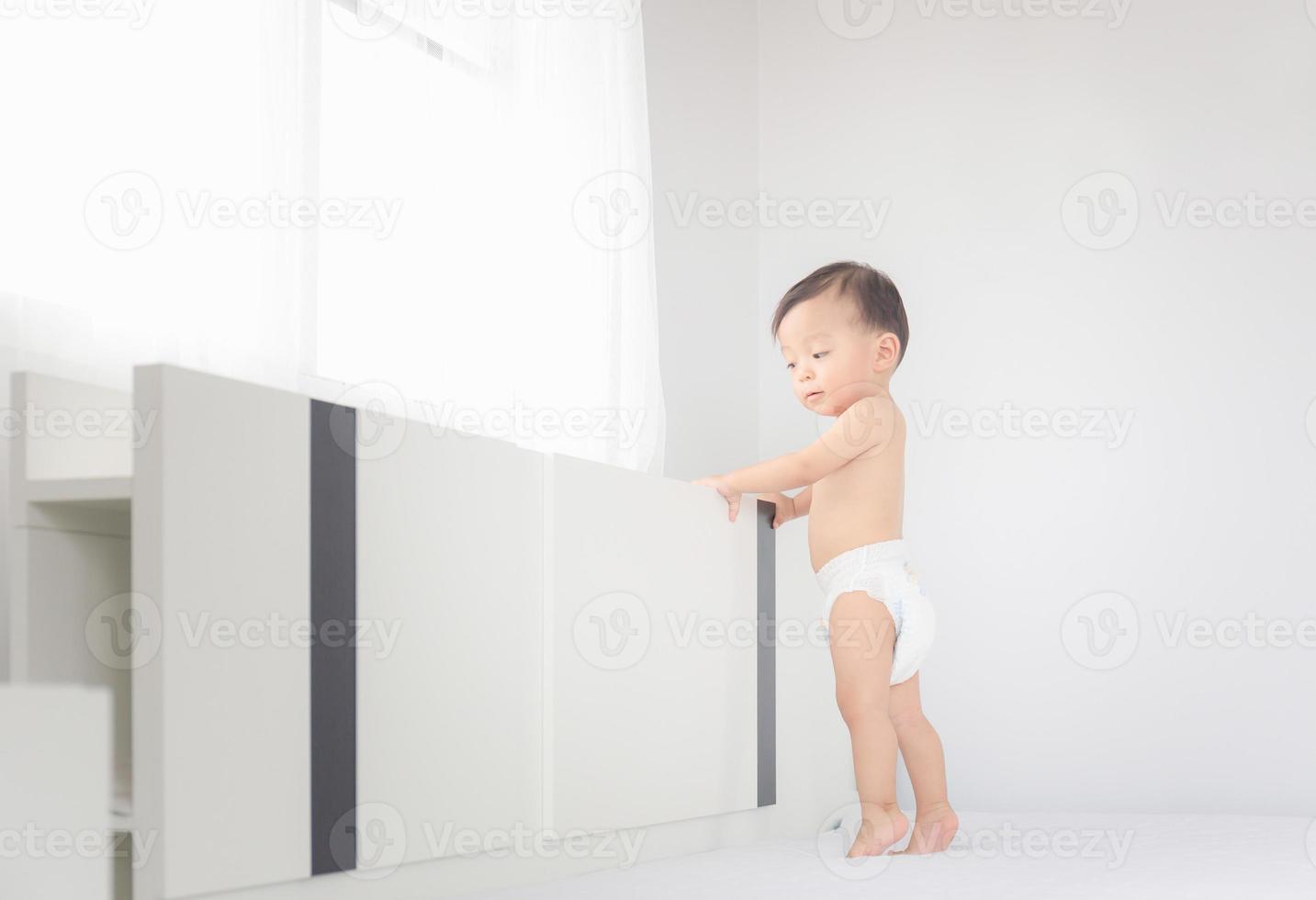retrato de un niño feliz con pañales parado en la cama, niños jugando y concepto de felicidad foto