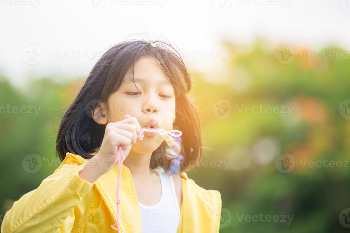 Cheerful a little girl blowing soap bubbles in the park, Kids playing concept photo