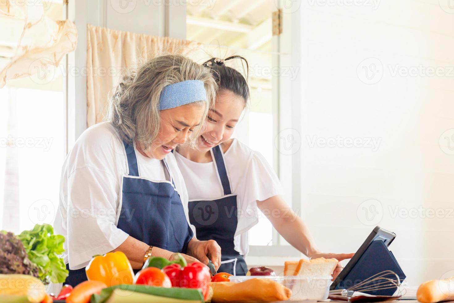 Senior asian mother and middle aged daughter cooking together at kitchen photo
