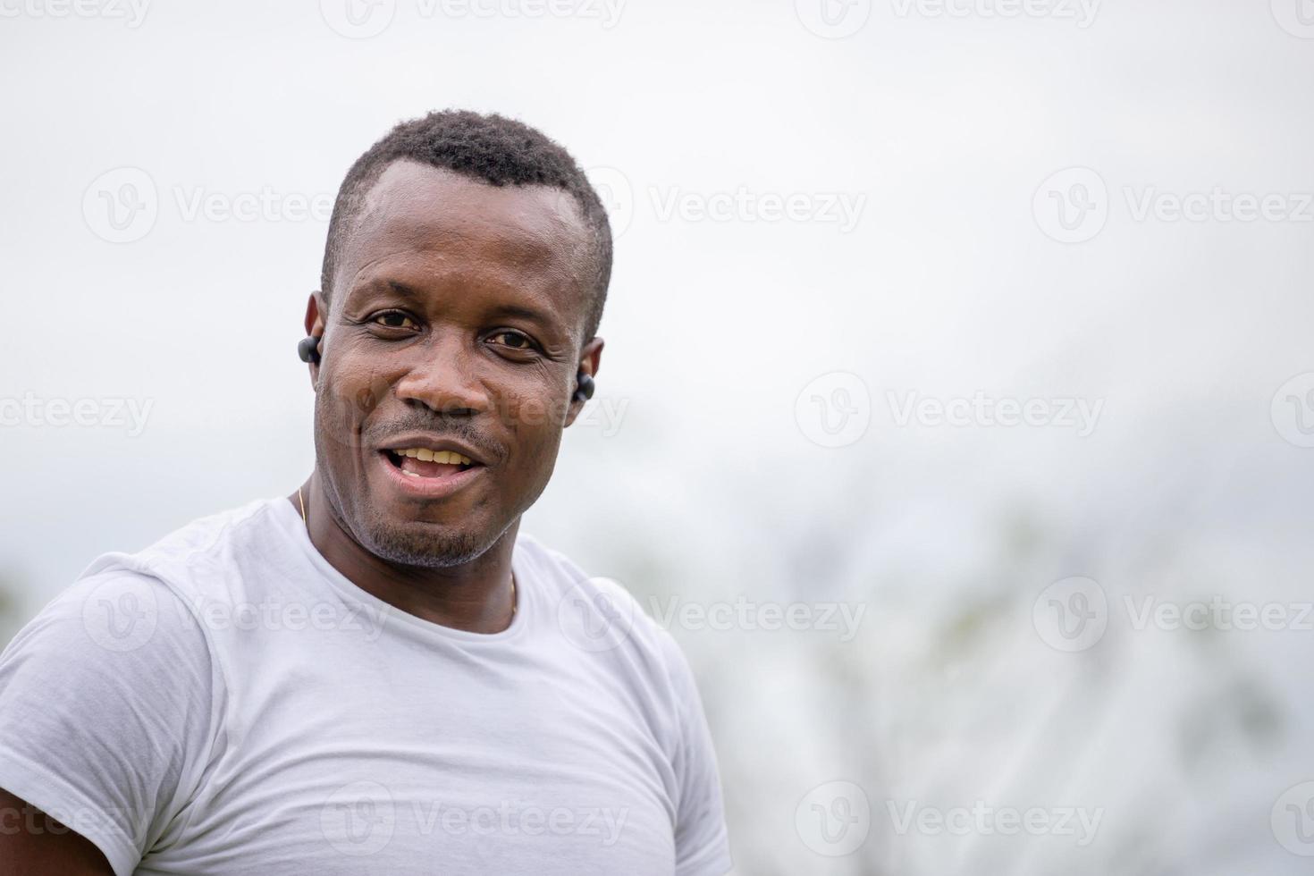 Cheerful african american man with wireless earpiece smiling at outdoor and looking at camera photo