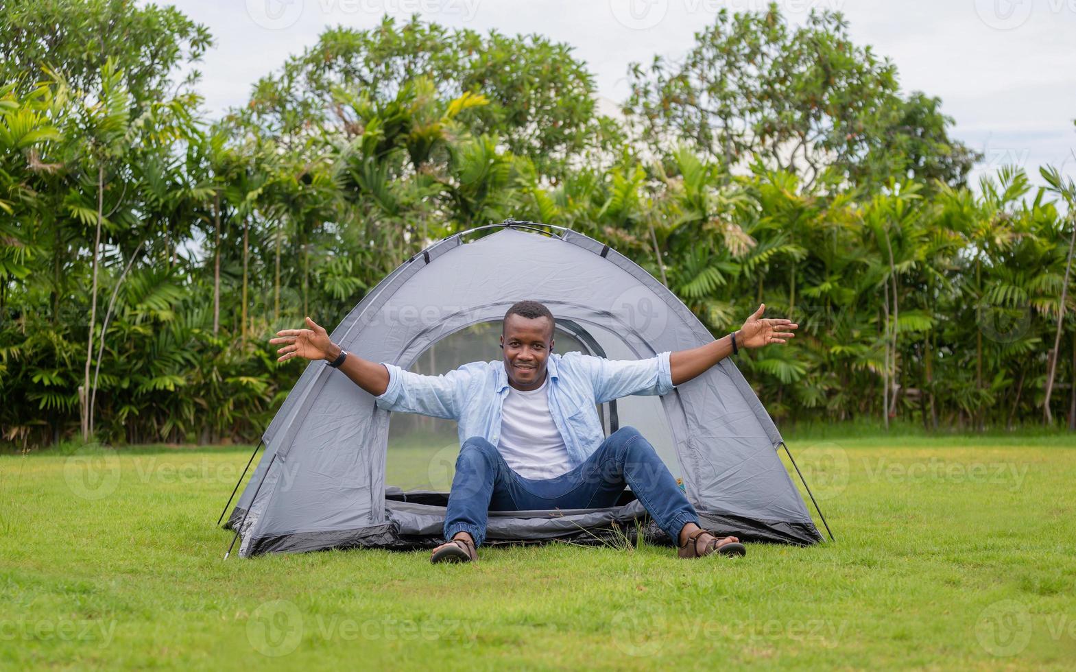 alegre hombre afroamericano disfrutando en una tienda, feliz camping al aire libre en el parque foto