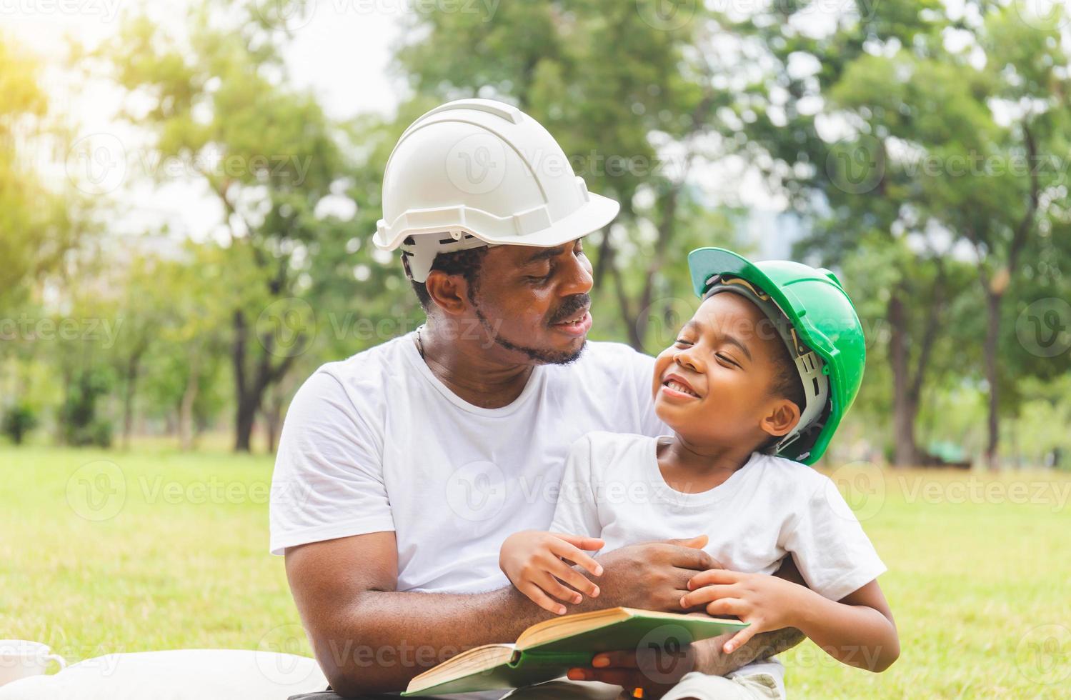 African american father and son in hard hat reading a book, Happy dad and son having a picnic in the park, Happiness family concepts photo