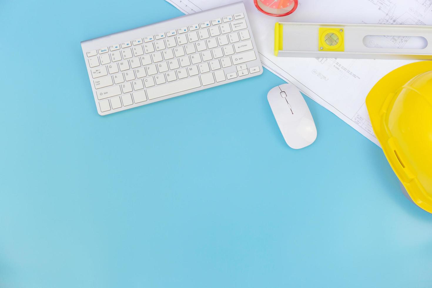 Top view with copy space of Engineering tools and computer keyboard, blueprints, helmet, measuring tape overhead on blue pastel background, Flat lay concept photo