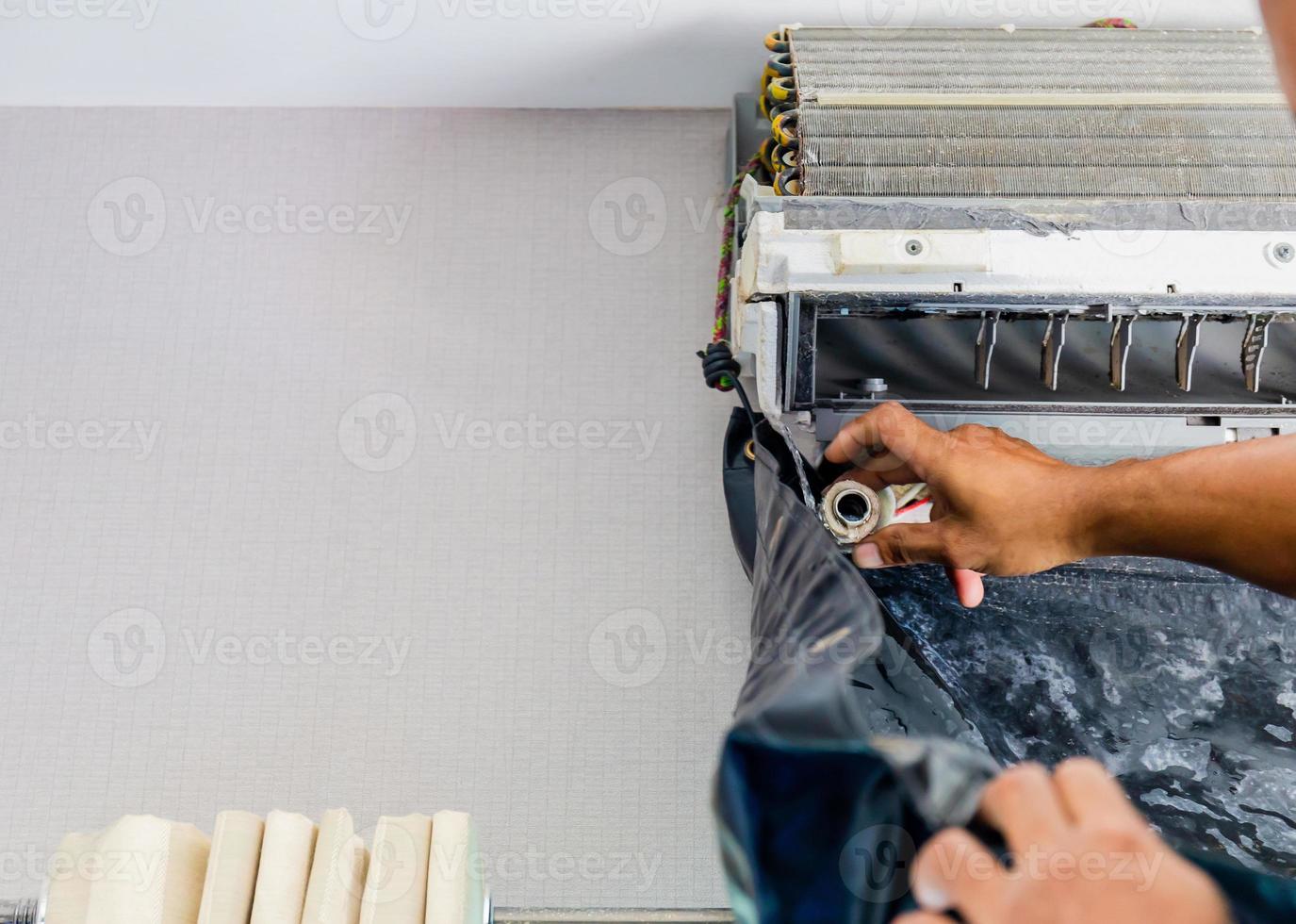 cierre de reparación de aire acondicionado, reparador revisando y limpiando un sistema de aire acondicionado de habitación foto
