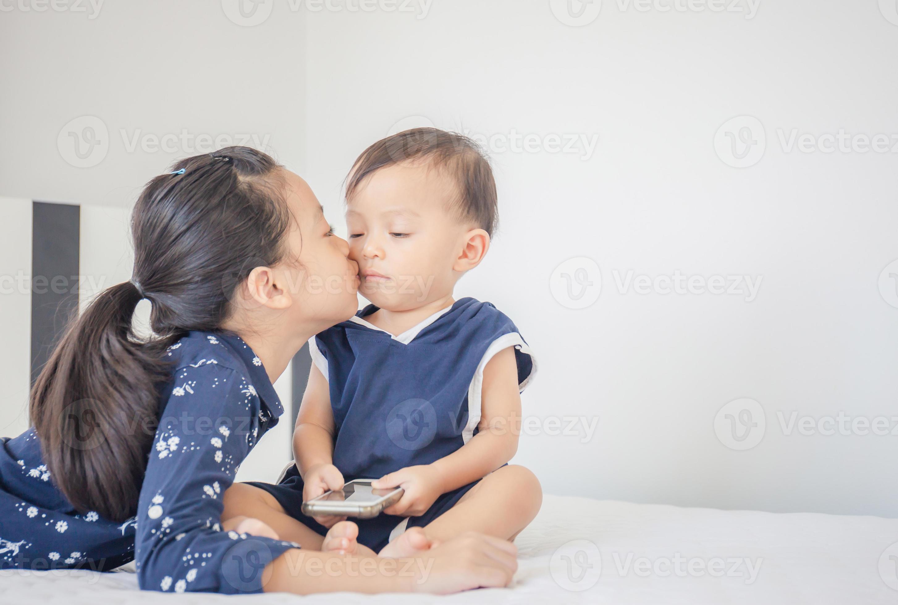 Sister kisses baby brother on the bed, happy family and kids playing ...