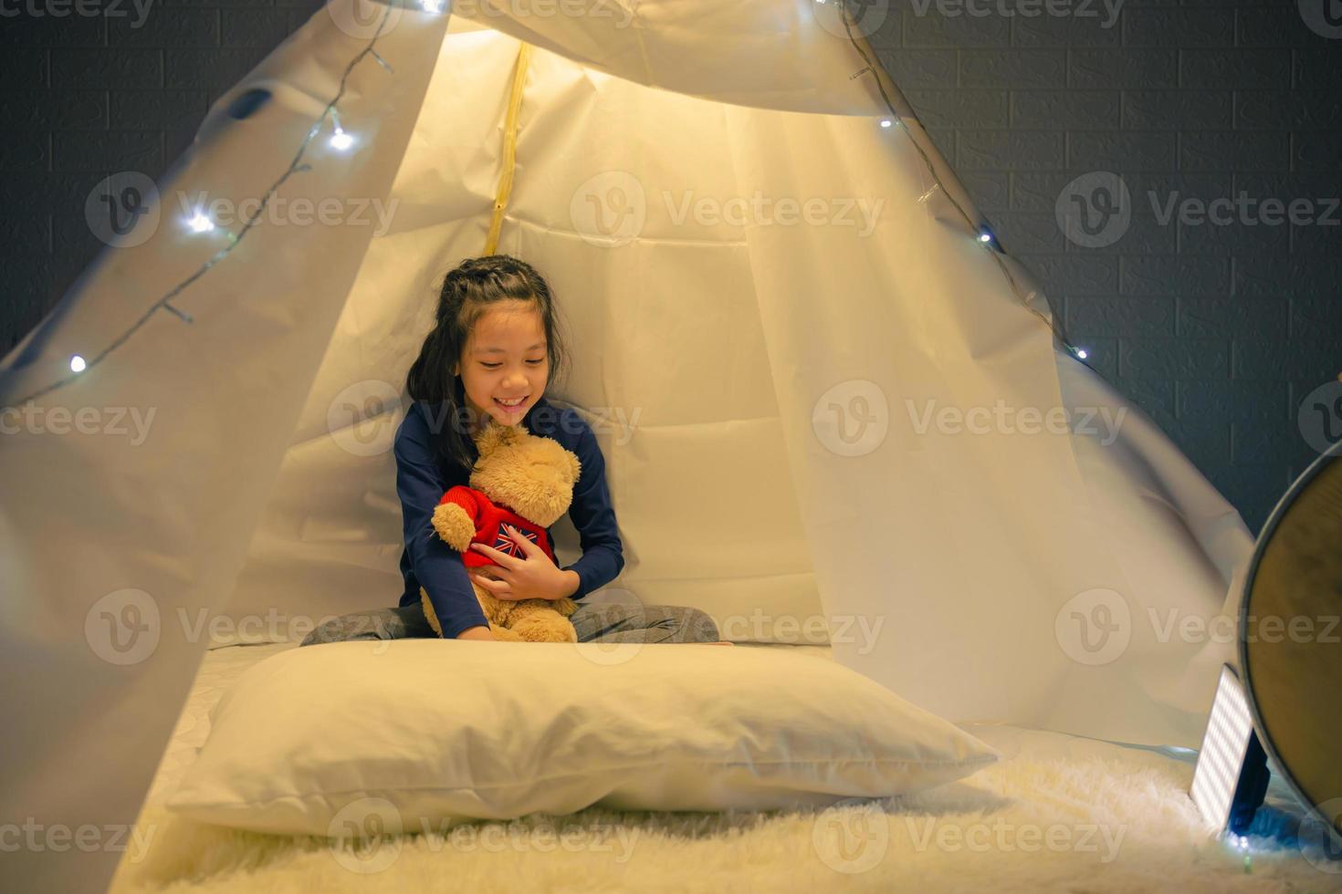 Little girl reading a book in tent, Happy kid playing at home, Funny lovely kid having fun in children room. photo