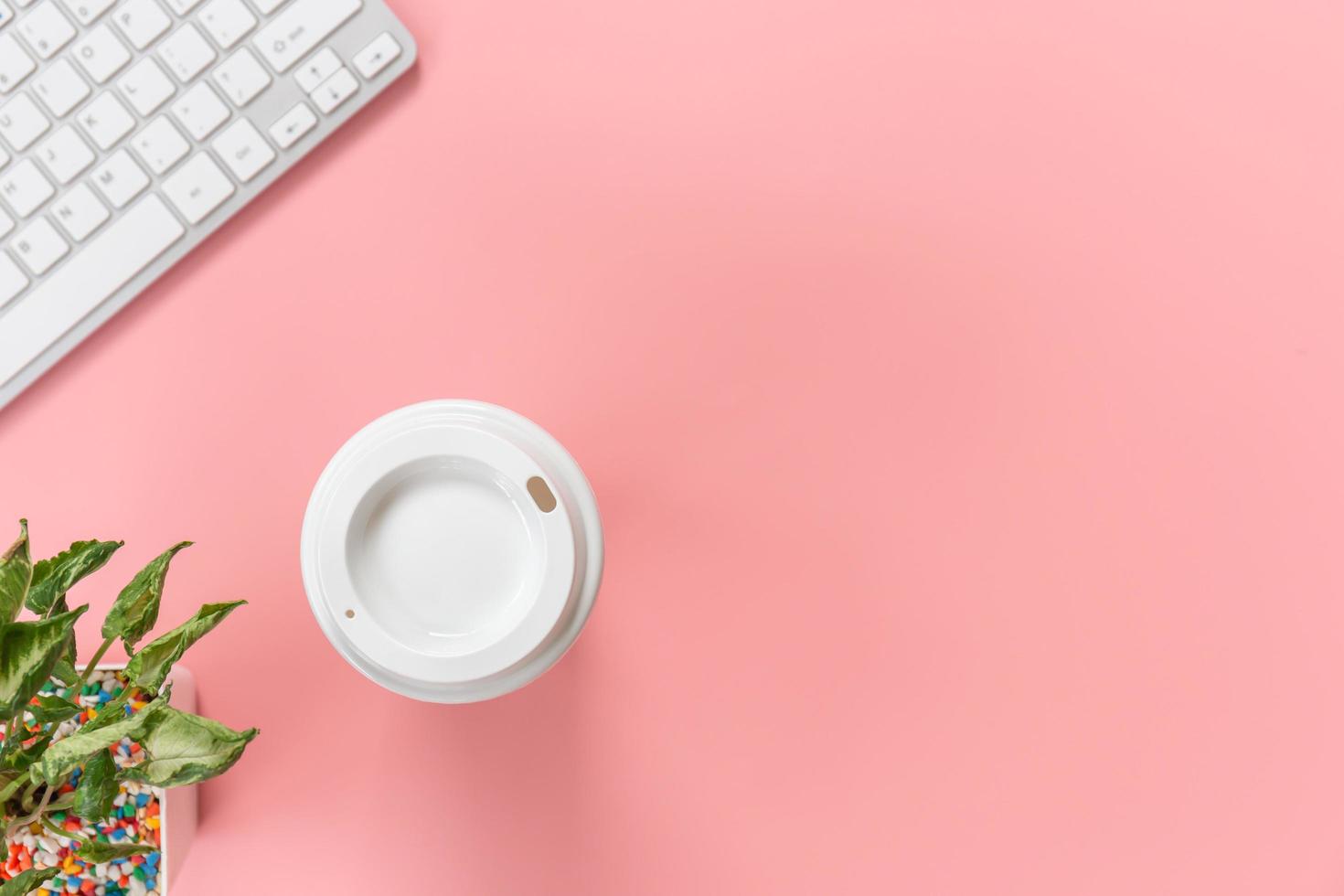 vista superior con espacio para copiar el teclado de la computadora y la taza de café sobre fondo rosa pastel, concepto plano foto