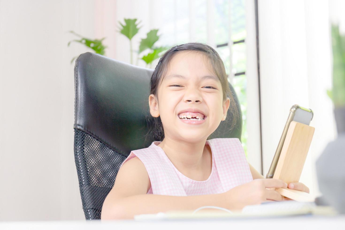 niña alegre sonriendo y mirando la cámara con alegría, felicidad y aprender del concepto de casa foto