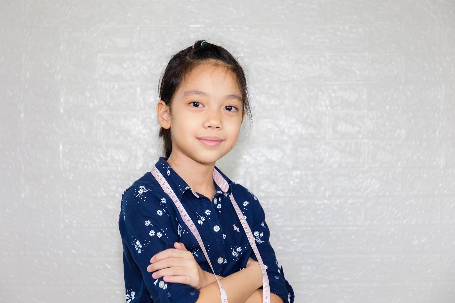 Dream careers concept, Portrait of Happy fashion designer kid with tailor measuring tape looking at camera on blurred background photo