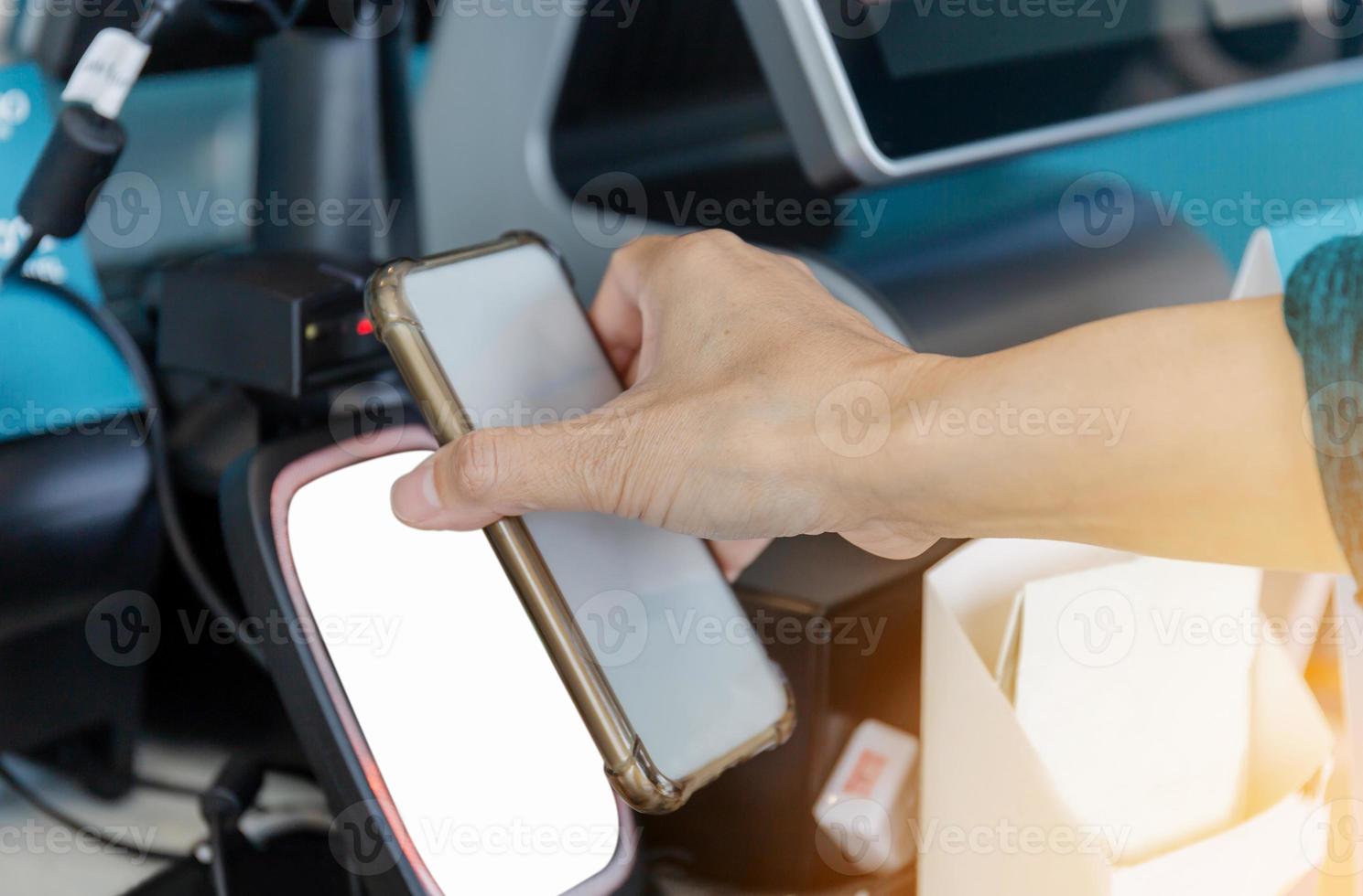 Close up of Woman hand paying with NFC technology on mobile phone in coffee shop, Female customer client pay in cafe with cellphone via pos machine photo