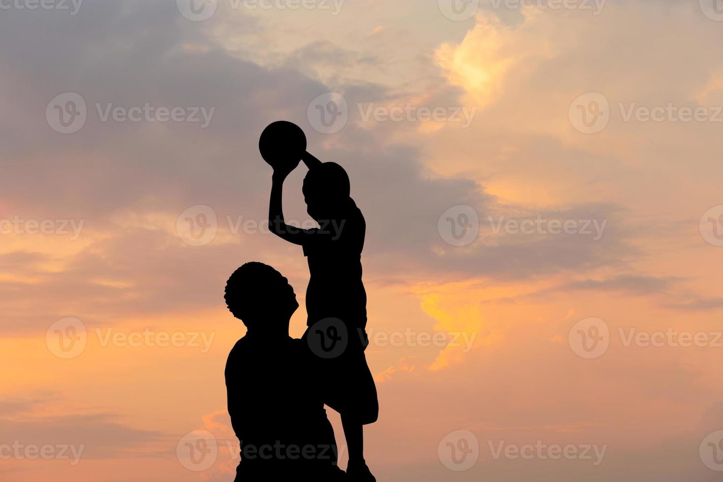 Silhouette of father and son with ball evening sky sunset background, Sport and enjoying life concepts. photo