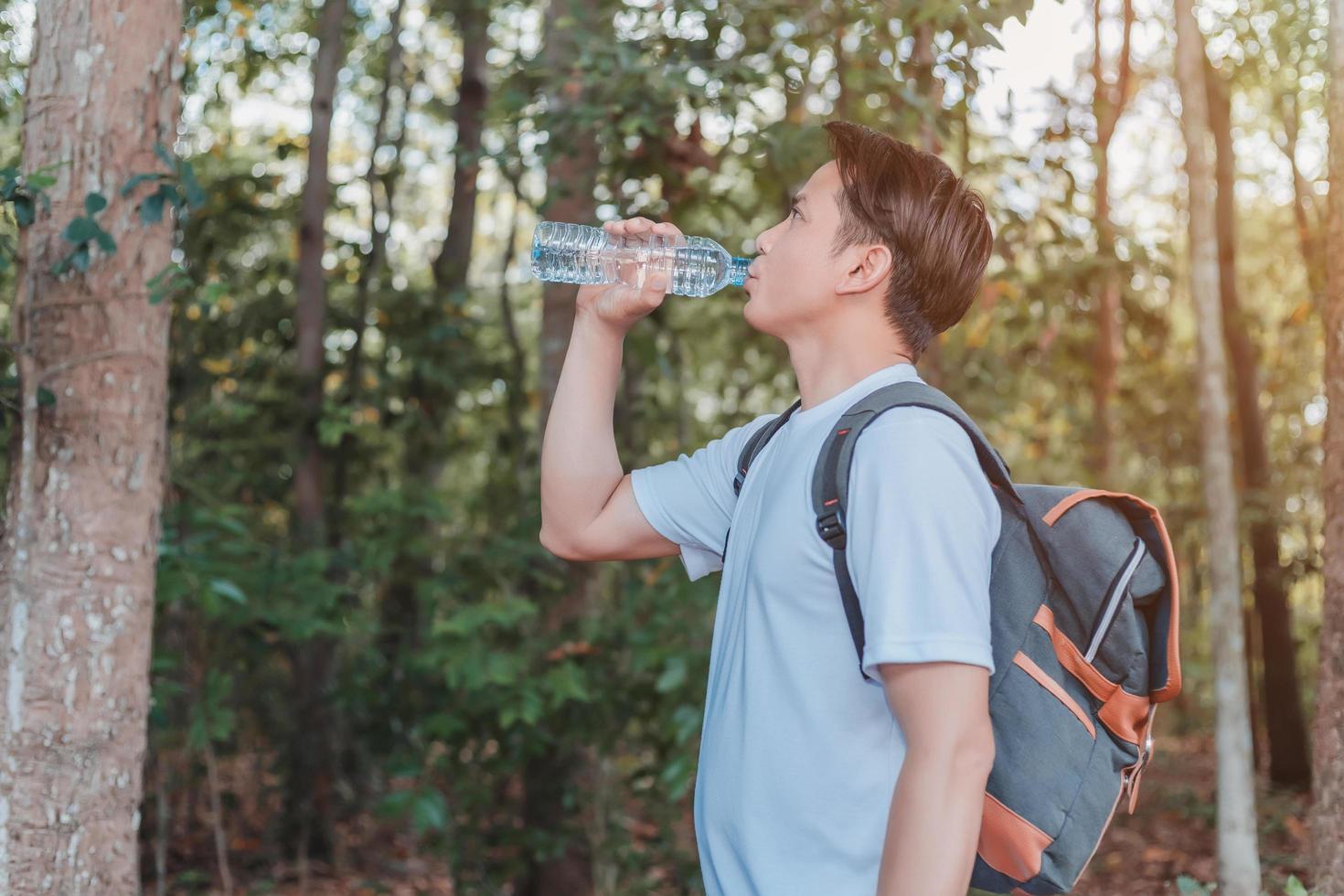 Male tourist carrying a bag drinking water in a bottle photo