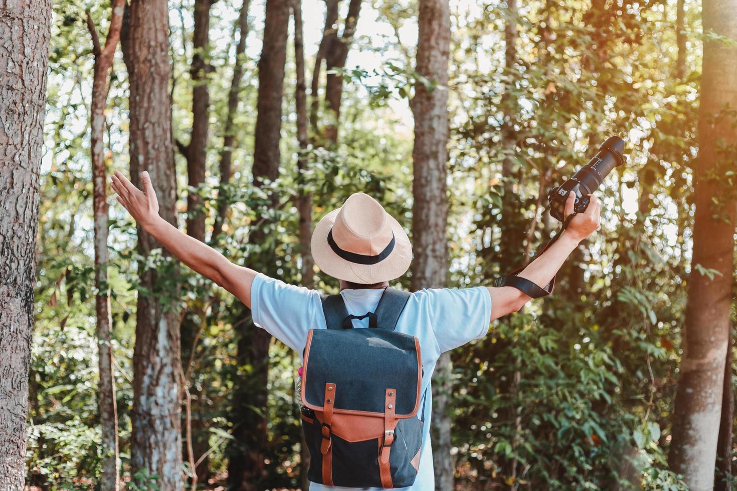 A male tourist carrying a handbag, water bottle and camera walks through the forest. photo