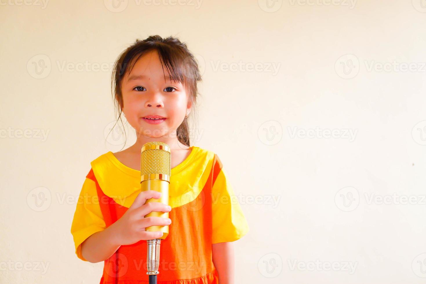 Lovely baby girl wears yellow-orange outfit gokowa outfit or Mugunghwa, and hold gold microphone singing music. Girls and teen fashion dress. photo