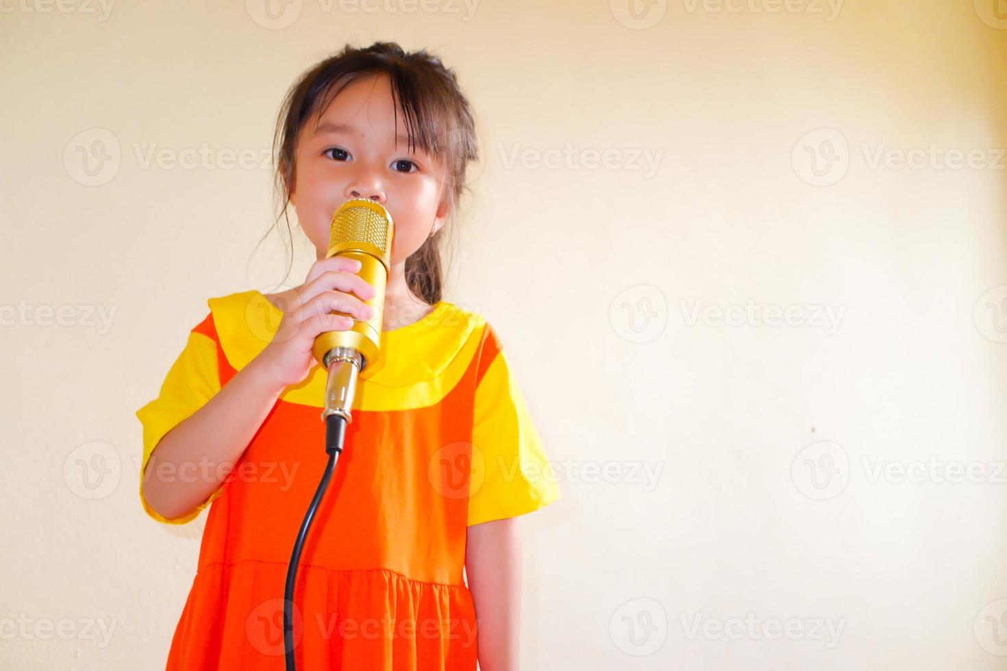 Lovely baby girl wears yellow-orange outfit gokowa outfit or Mugunghwa, and hold gold microphone singing music. Girls and teen fashion dress. photo