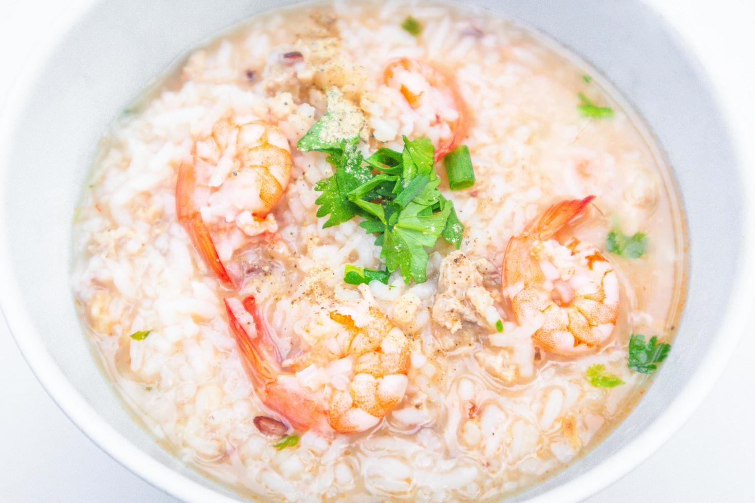 Boiled rice soup with shrimps and minced pork in white bowl. Popular Thai breakfast photo