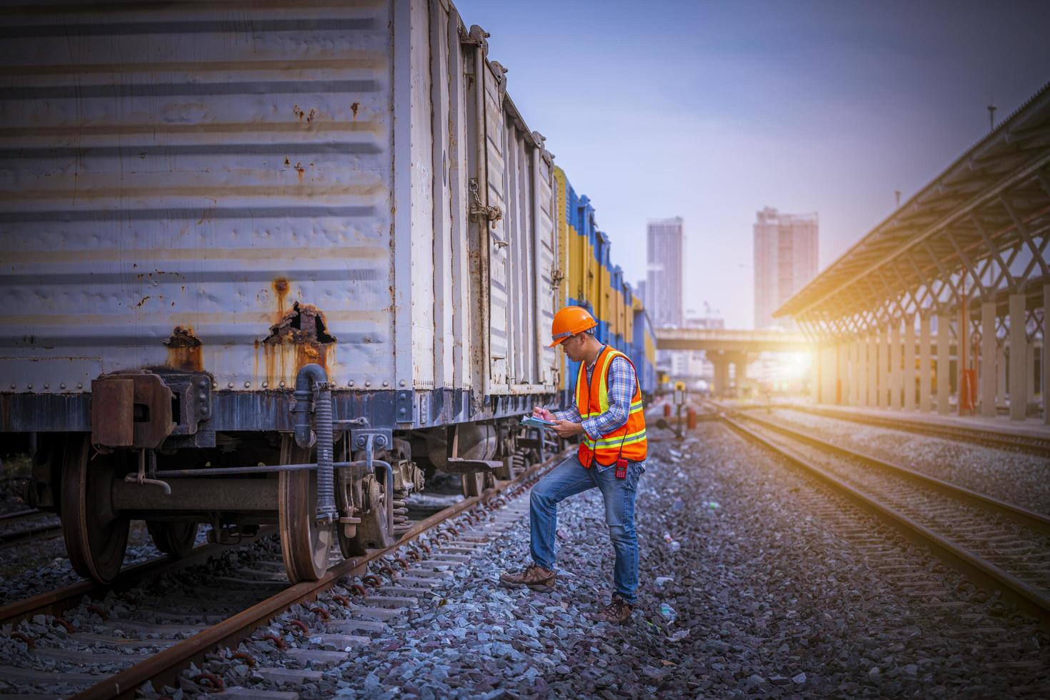 ingeniero ferroviario bajo control del proceso de construcción prueba de trenes y control del trabajo ferroviario en la estación de ferrocarril con comunicación por radio. ingeniero con uniforme de seguridad y casco de seguridad en el trabajo. foto