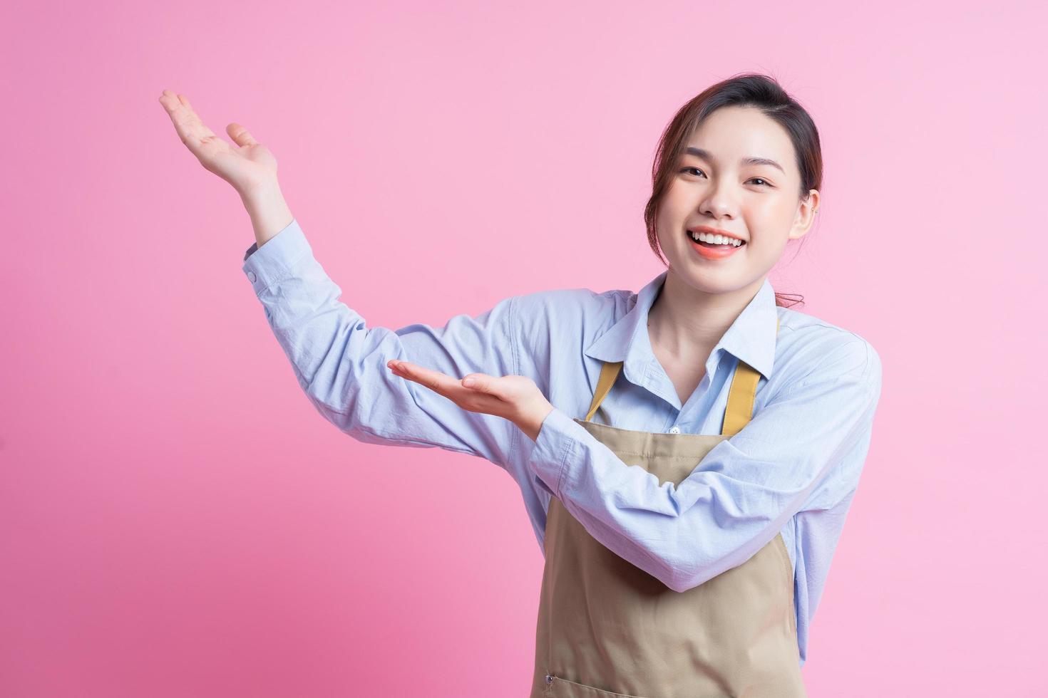Young Asian waitress standing on pink background photo