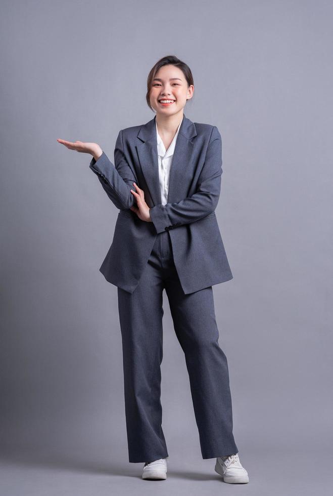 Young Asian business woman standing on gray background photo