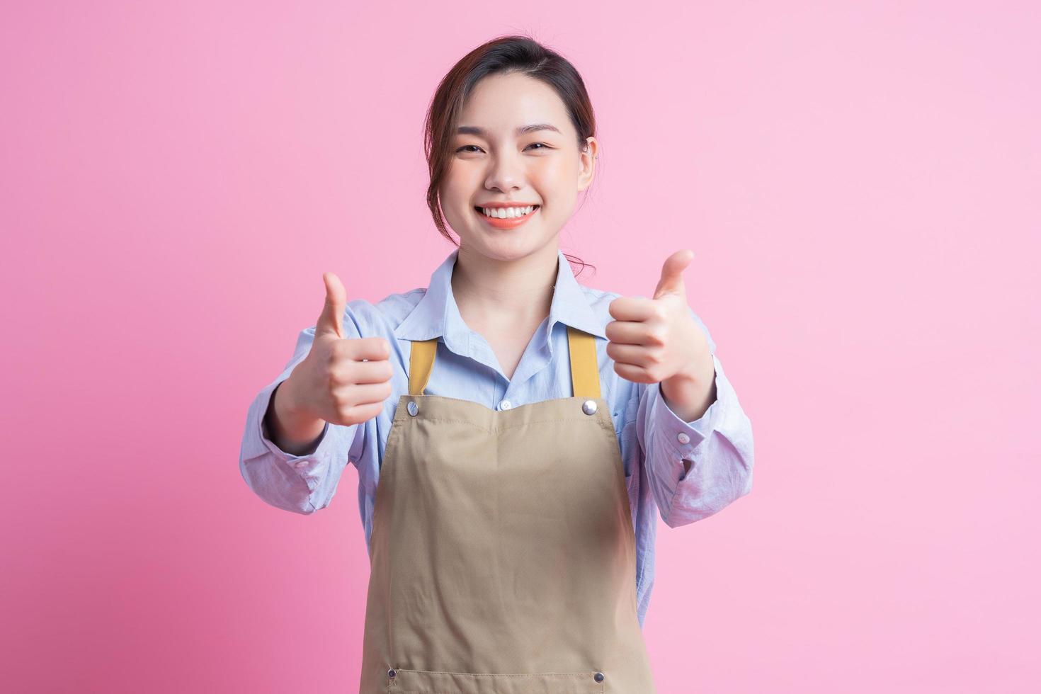 Young Asian waitress standing on pink background photo