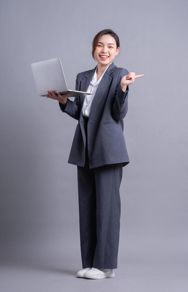 Young Asian business woman standing on gray background photo