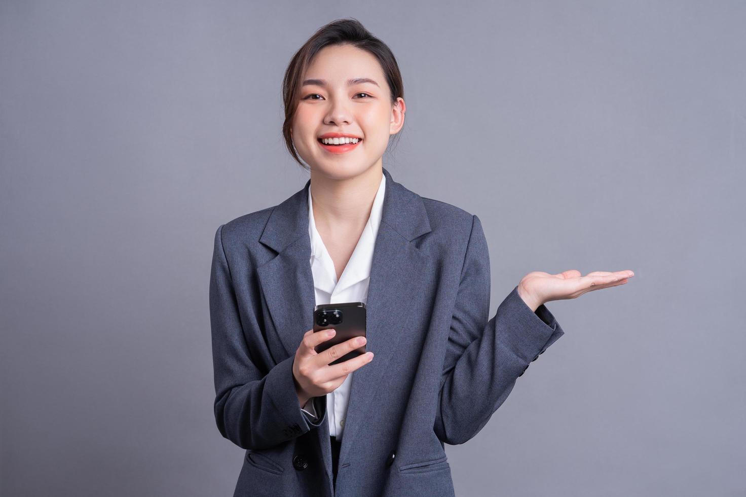 joven empresaria asiática sosteniendo un teléfono inteligente con fondo gris foto