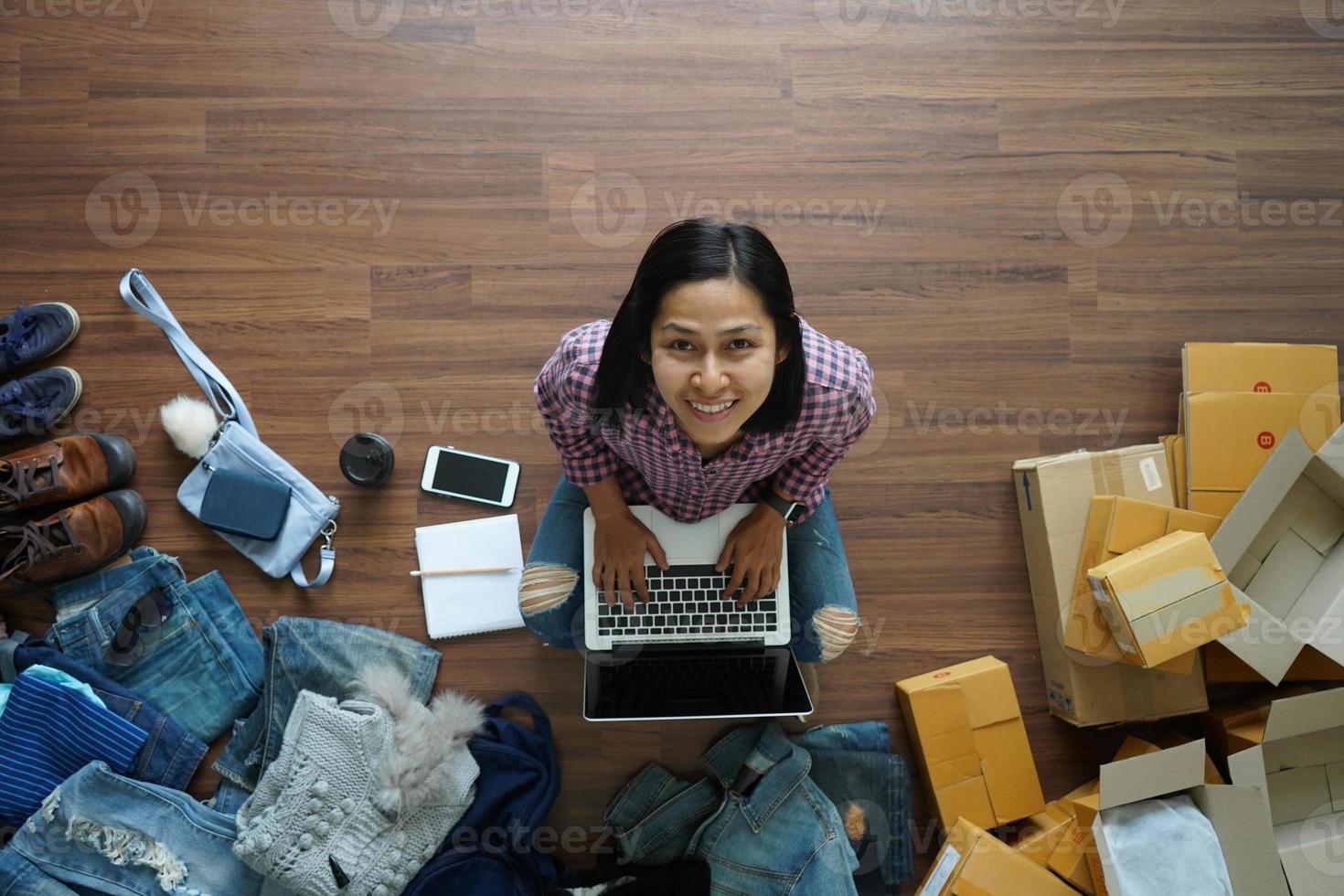 Top view of women working laptop computer from home on wooden floor with postal parcel, Selling online ideas concept photo