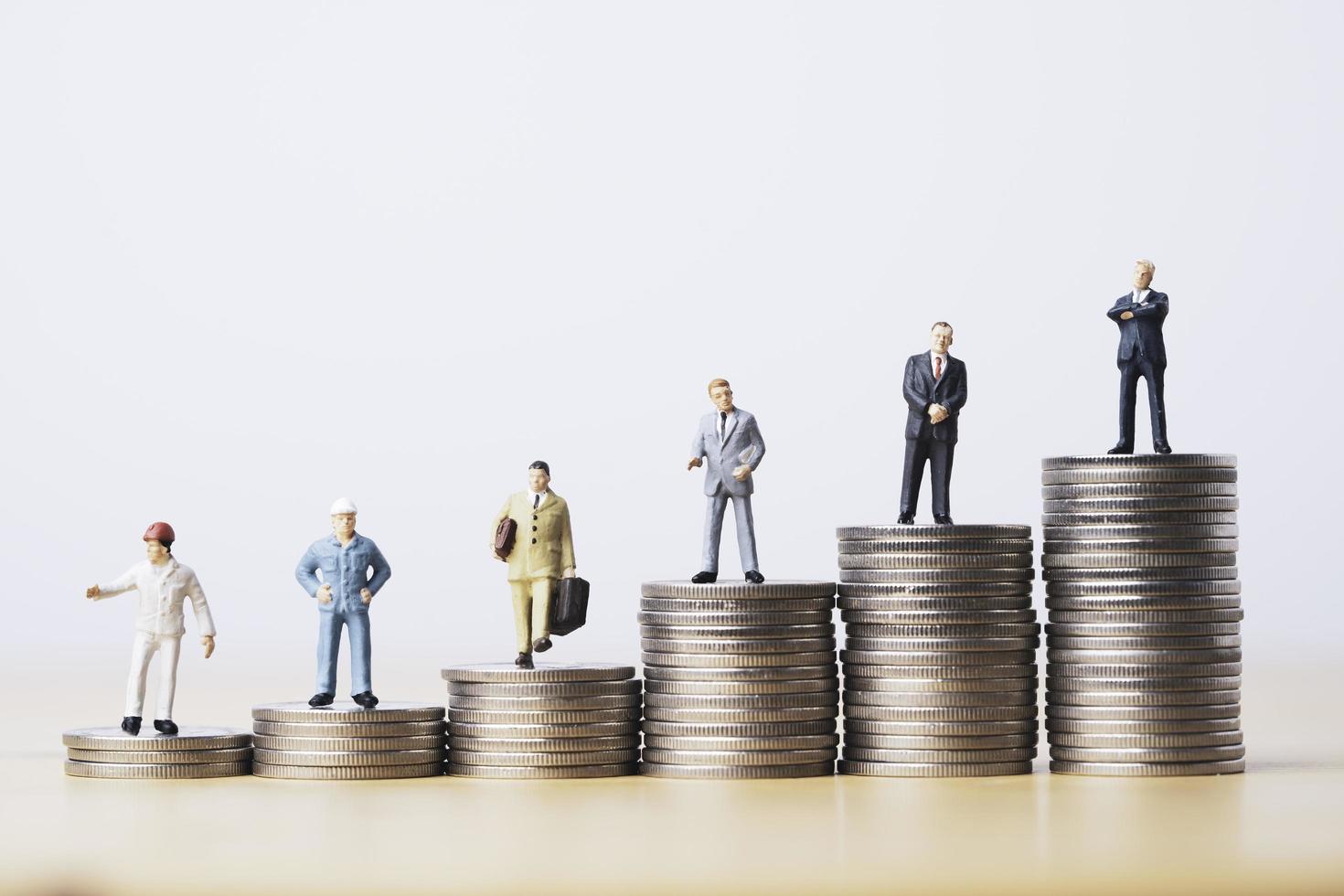 worker technician businessman and management miniature figure standing on different coins stacking for symbol of various income in each job level concept. photo