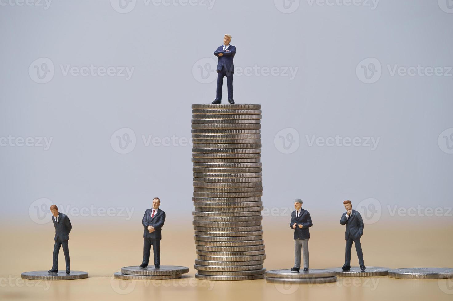Miniature figure of five businessmen standing to different high and low coins stacking for position and successful business investment income concept. photo