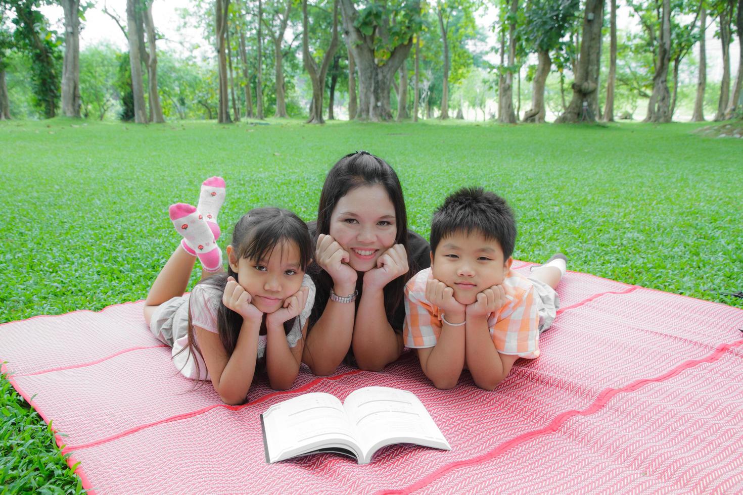 Mother daughter and son reading a book in the garden. photo