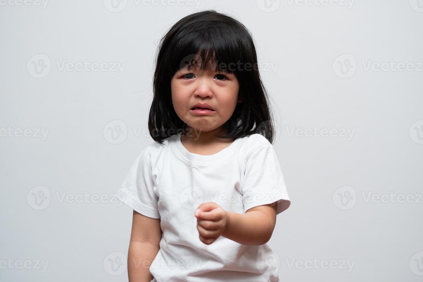 Portrait of Asian angry, sad and cry little girl on white isolated background, The emotion of a child when tantrum and mad, expression grumpy emotion. Kid emotional control concept photo