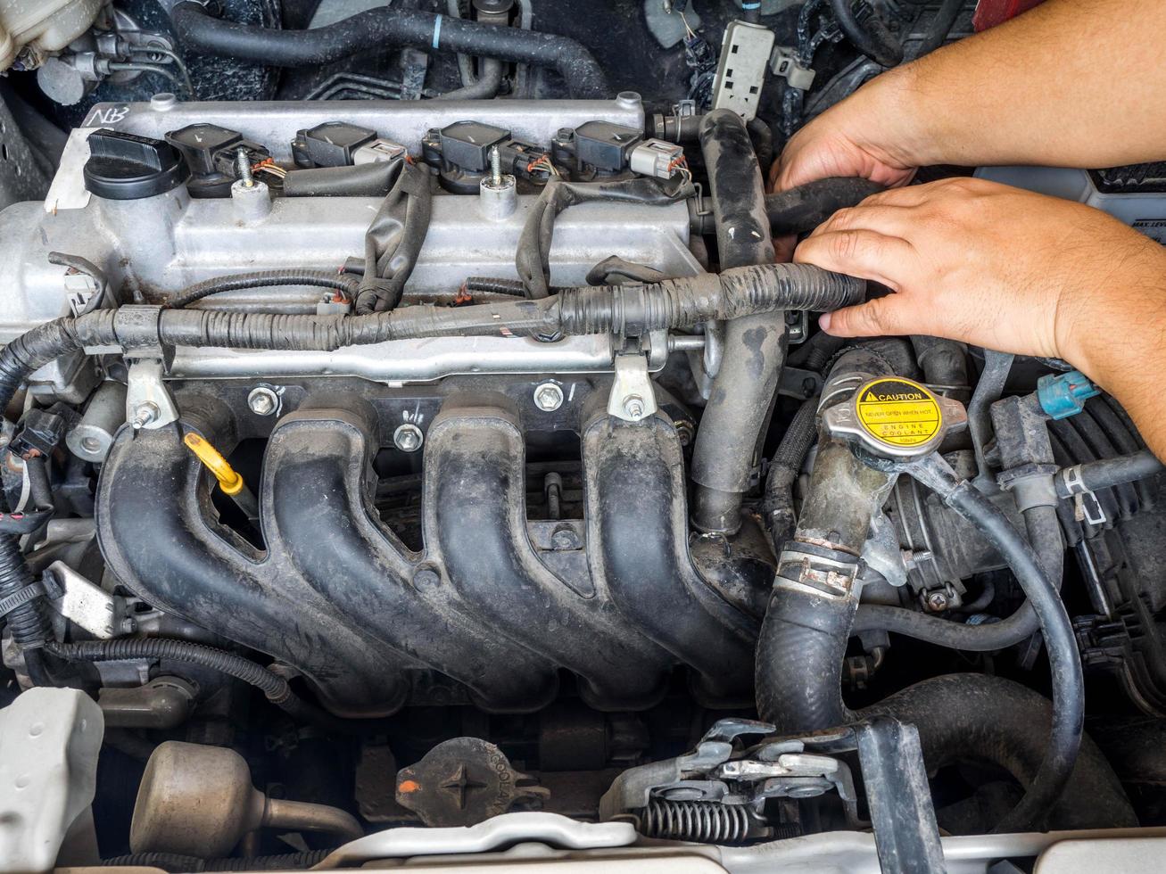 Hand of car mechanic working in auto repair service. He have fix old car engine streaked with dust and oil stains photo