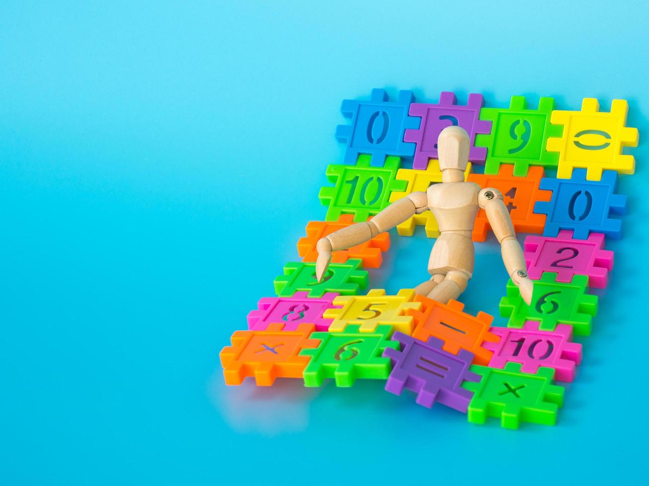 Wooden puppet sleep in color full plastic number on blue background. Concept of education. copy space for text and content. photo