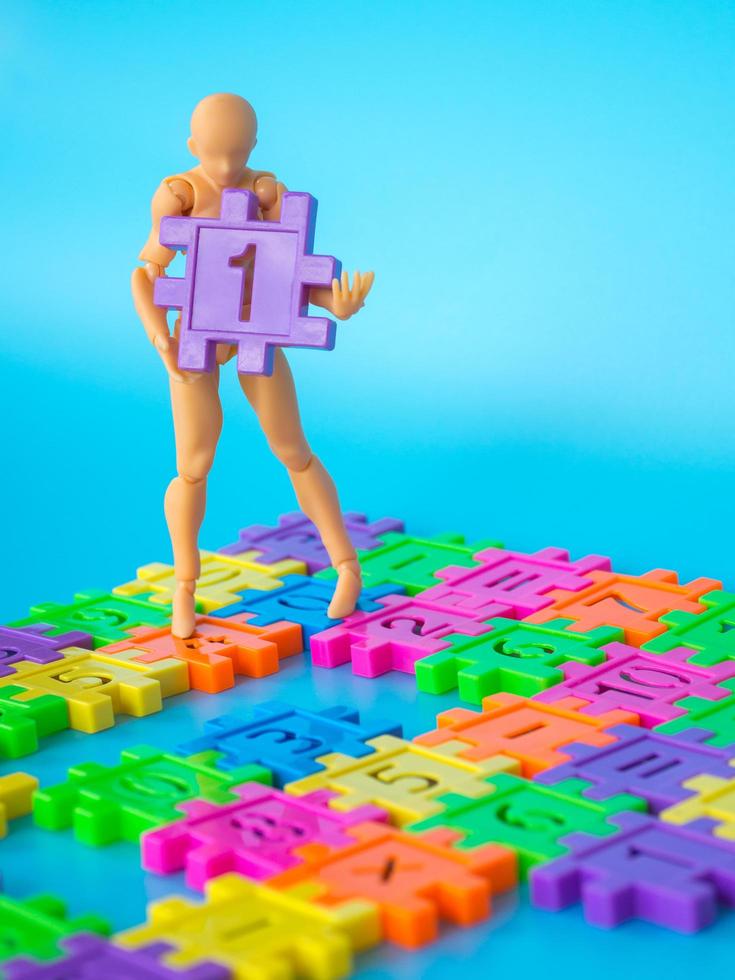 action figure stand on colorfull plastic number and hold purple plastic number one on blue background. Concept of education. copy space for text and content. photo