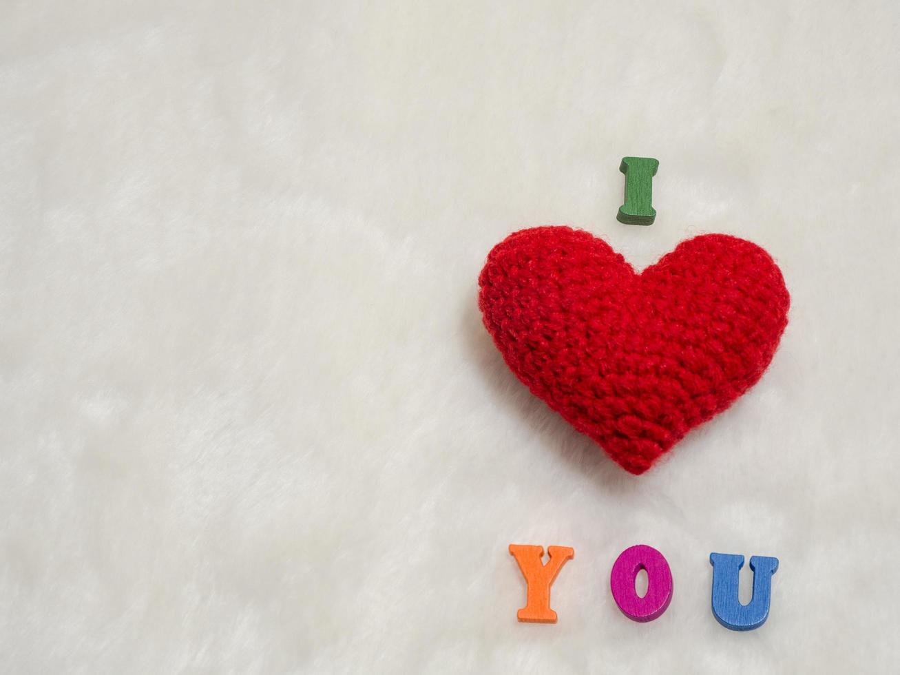red yarn heart on white wool and alphabet I LOVE U. the red heart on the right of picture and background copy space for text. Valentines day, love concept and love background photo