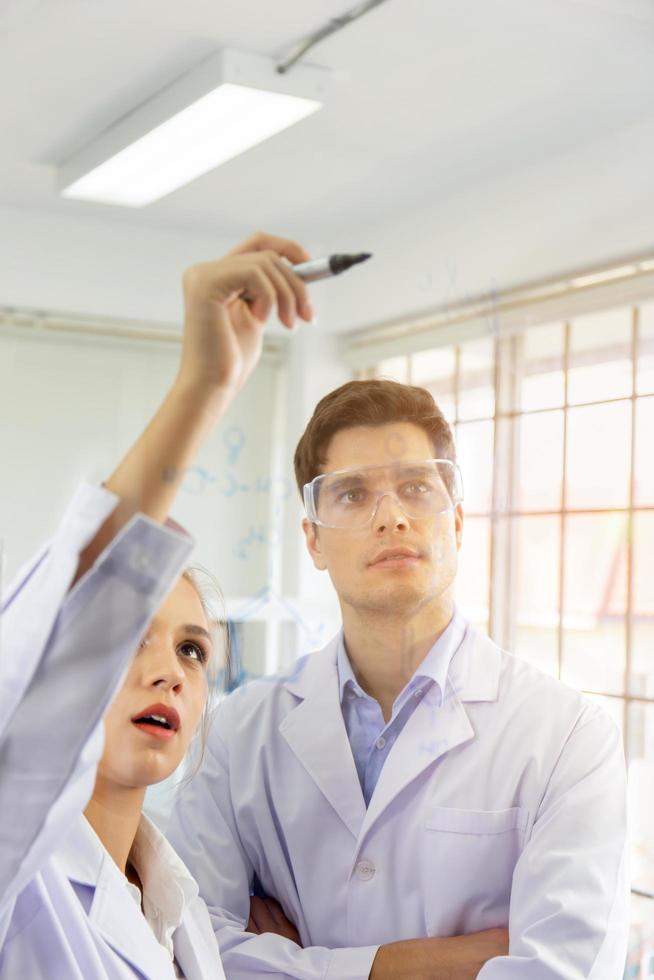 Close-up, a group of young scientists and young men are recording formulas on a glass board and have an orange light. photo