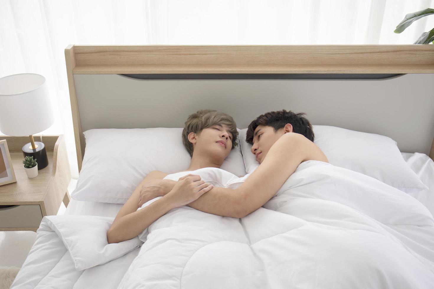 A male couple with an Asian man cuddling next to their bed, a symbol of sexual diversity, expressing openly gay men accepting LGBT concepts. photo