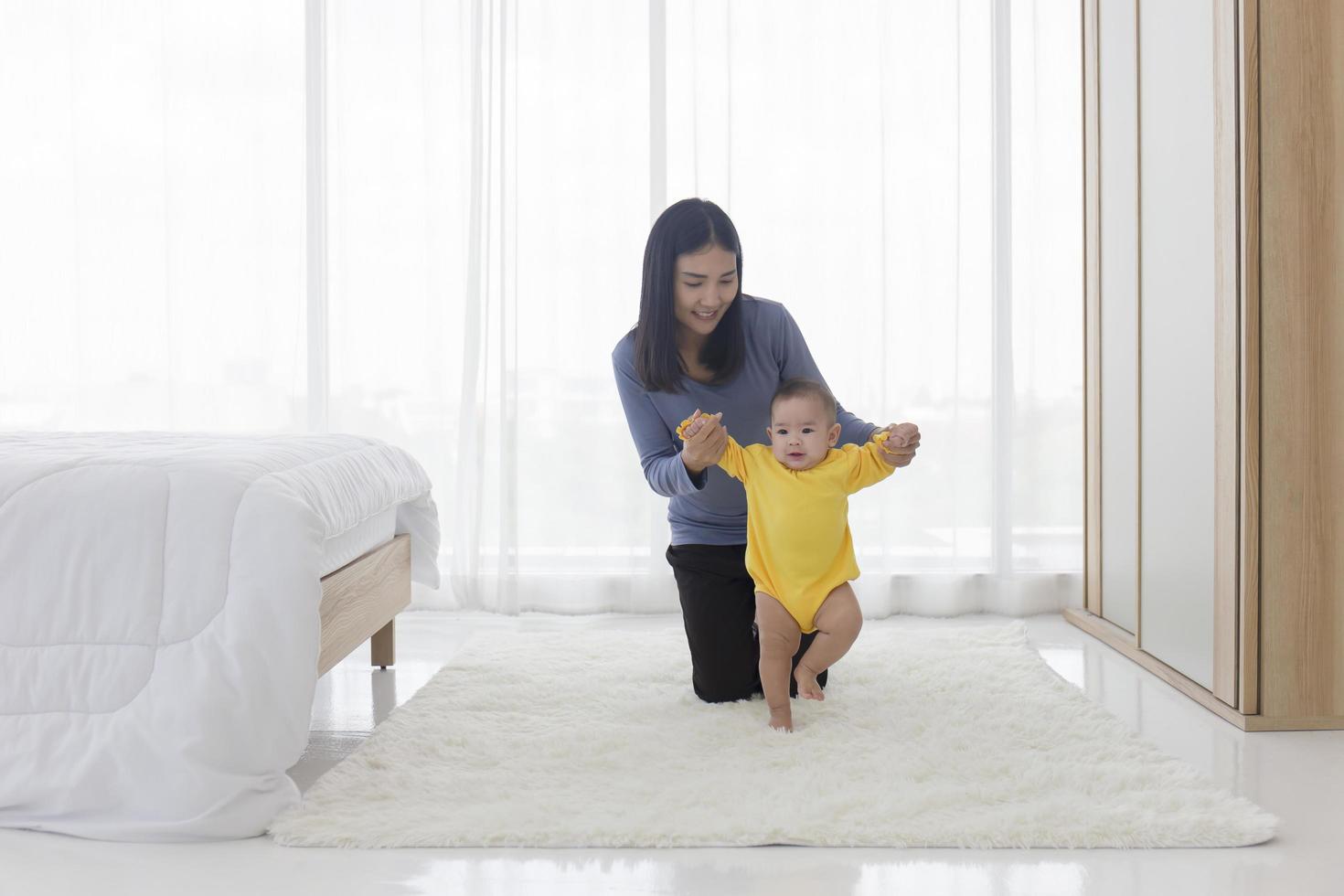 An Asian mother is helping to support her baby to learn to walk in a joyful manner. photo