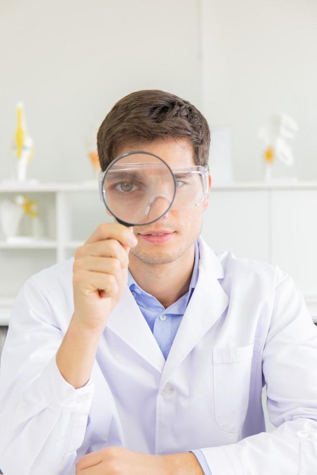 The male doctor looking through the magnifying glass in the lab photo